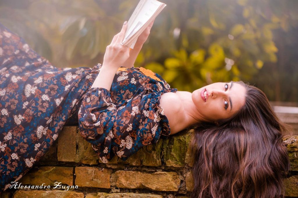 ragazza distesa su un muretto mentre posa per book fotografico autunnale